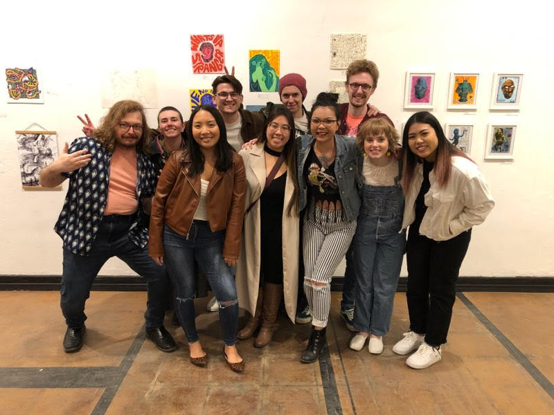Group of happy artist friends in front of paintings